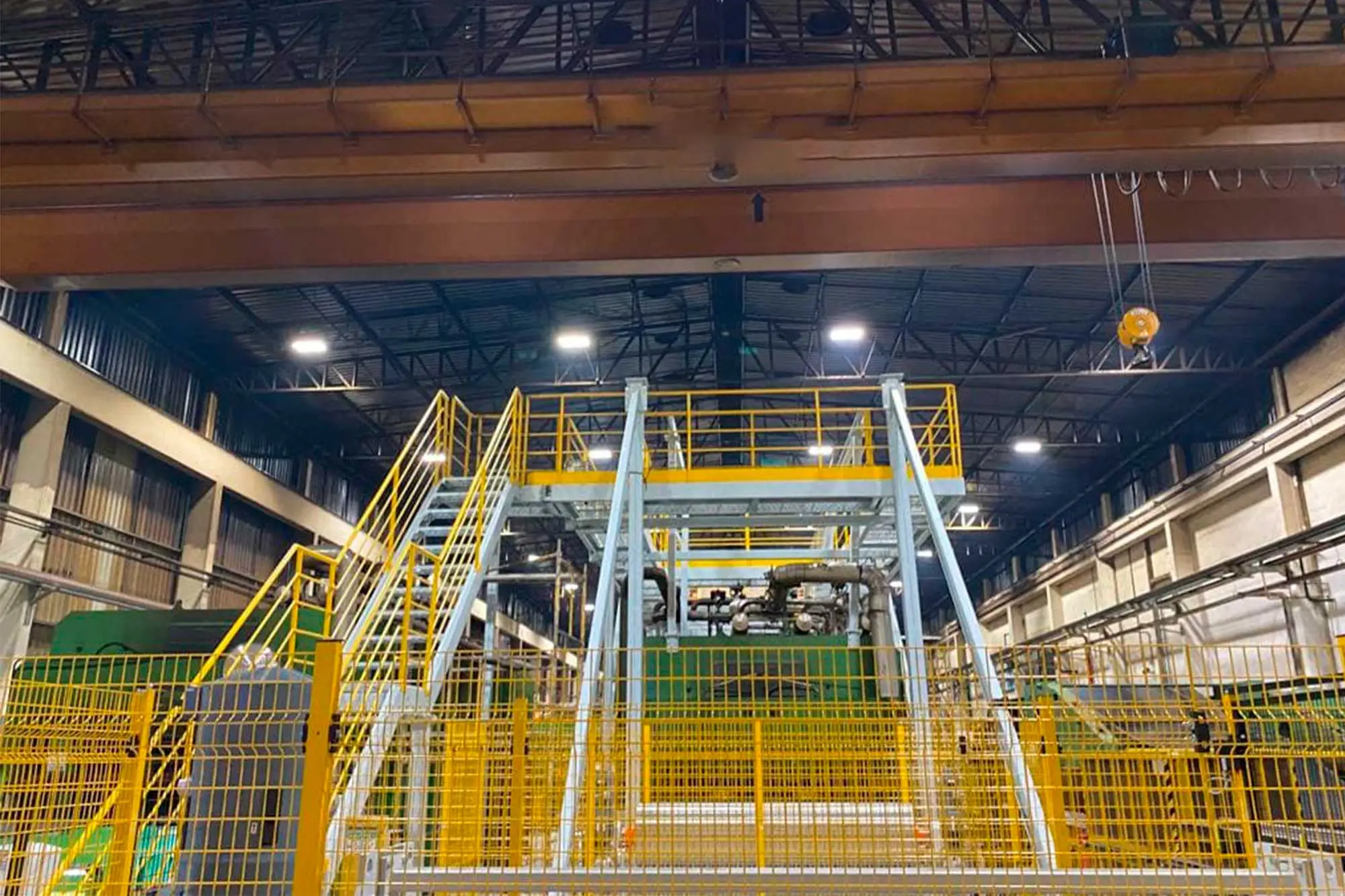 Plataforma industrial com escada, guarda-corpos e proteções metálicas amarelas