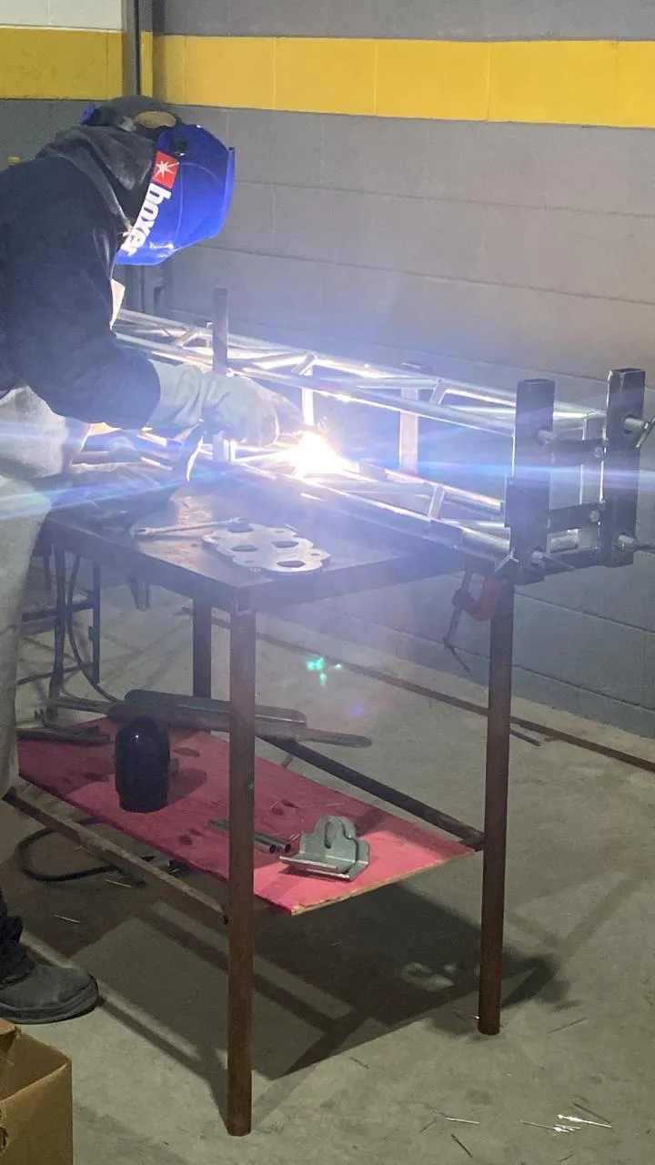 Profissional soldando treliça metálica tubular em oficina
