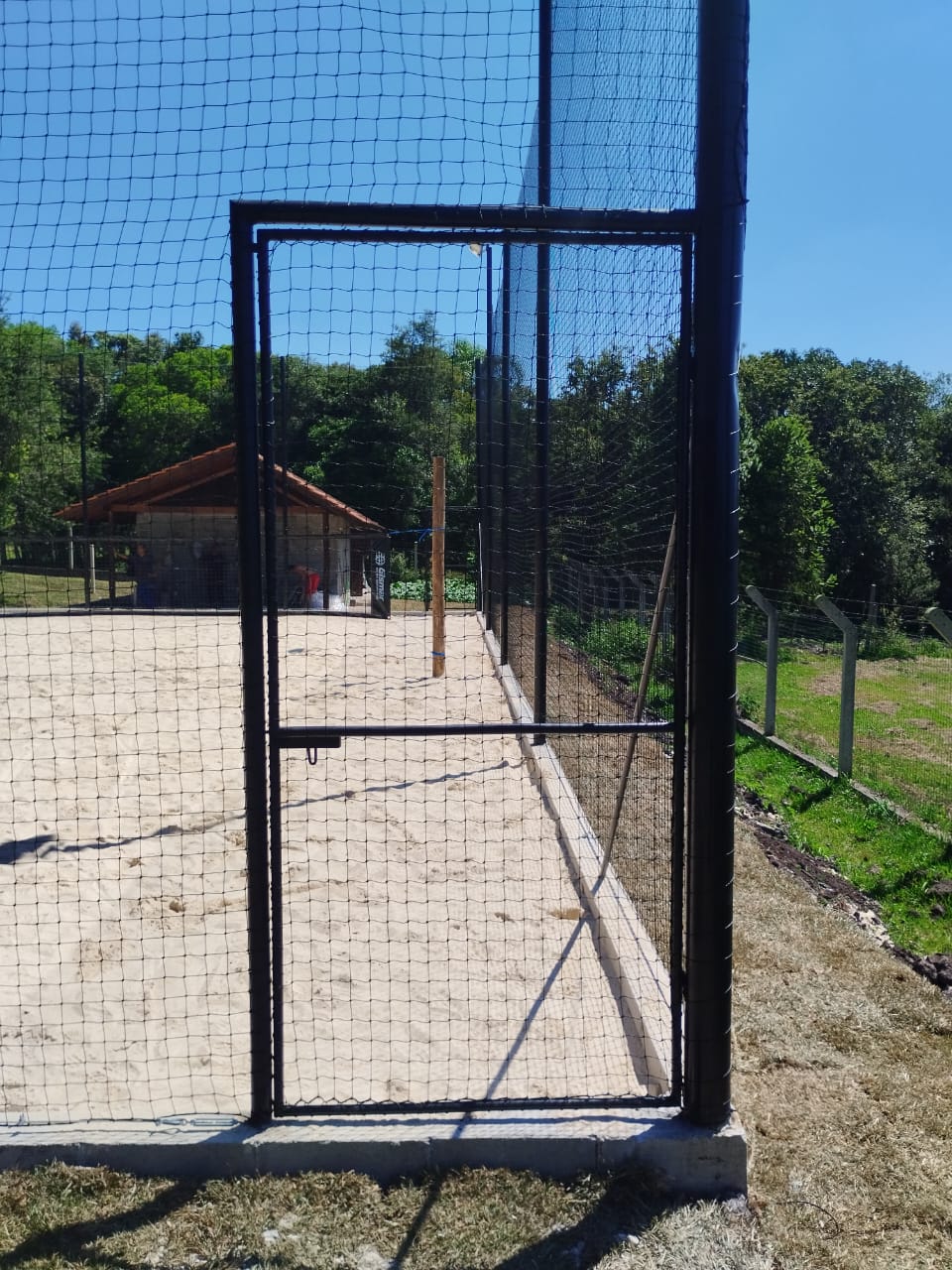 Portão metálico com tela instalado em quadra esportiva