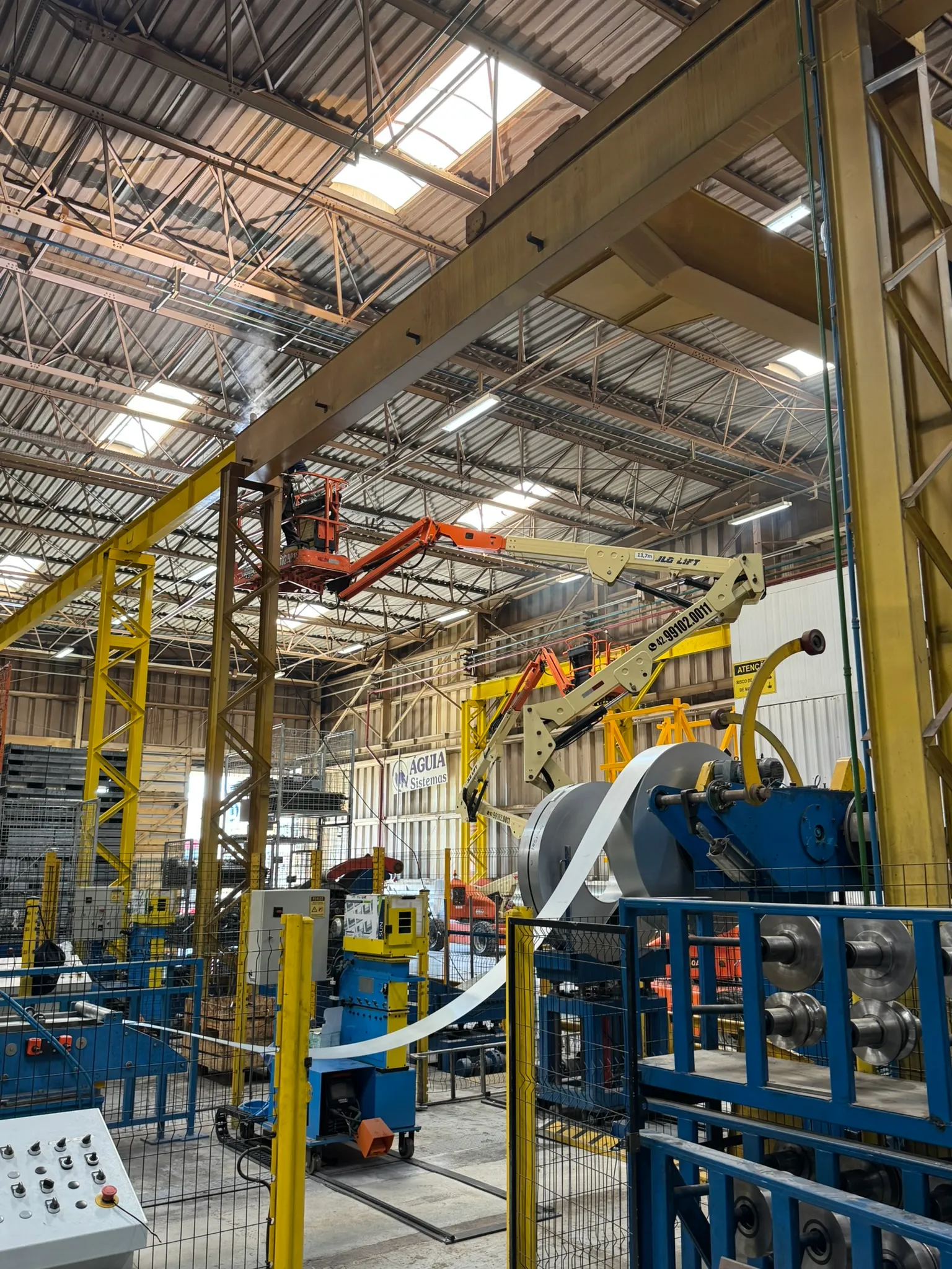 Estrutura metálica amarela em área industrial com equipamentos de elevação