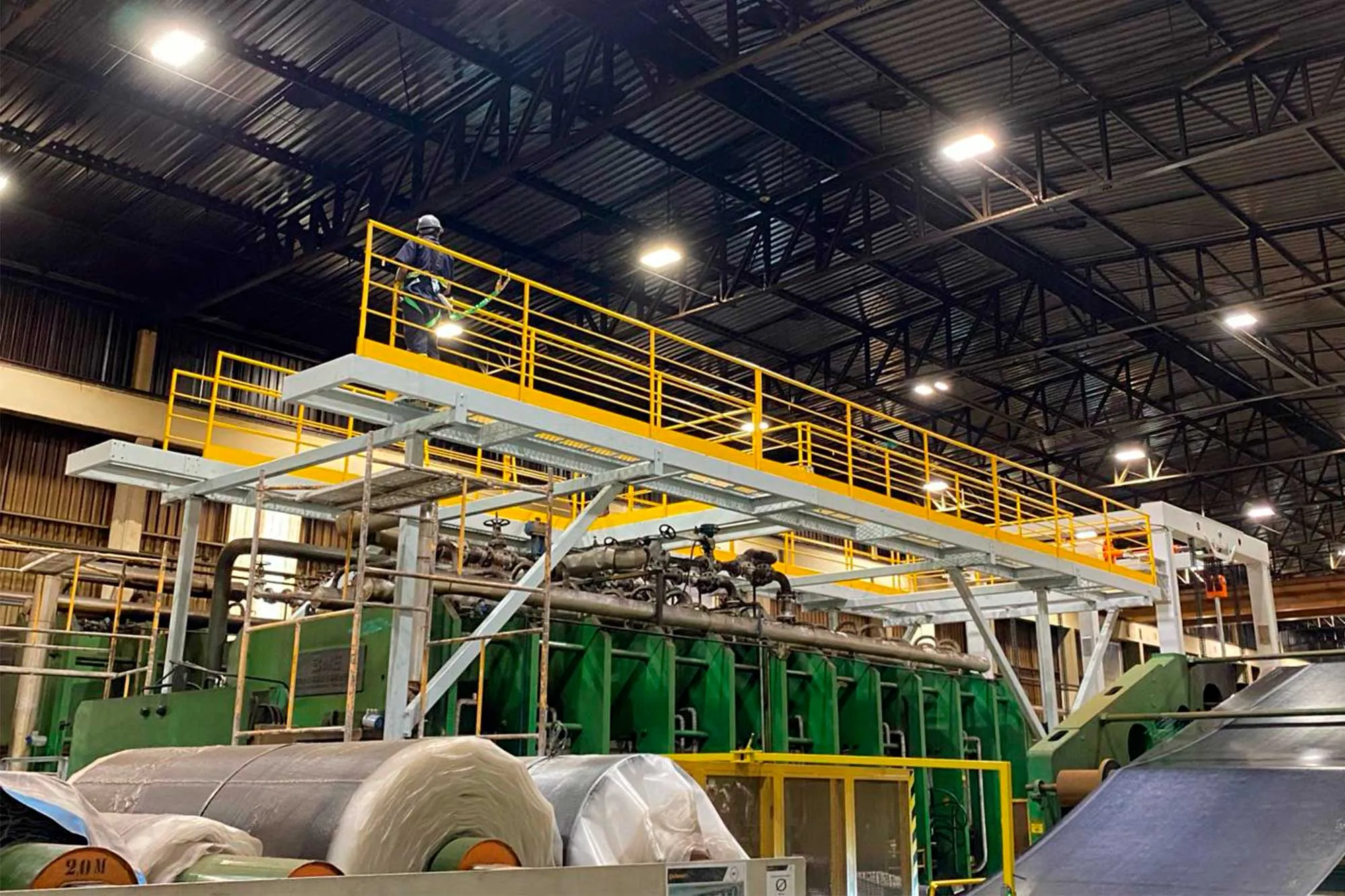 Plataforma metálica elevada com guarda-corpos amarelos instalada sobre equipamentos industriais